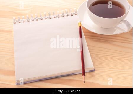 Mockup image. Open blank page notebook with a copy space and cup of tea on a white wooden table background. Empty open notebook with a red pencil and Stock Photo