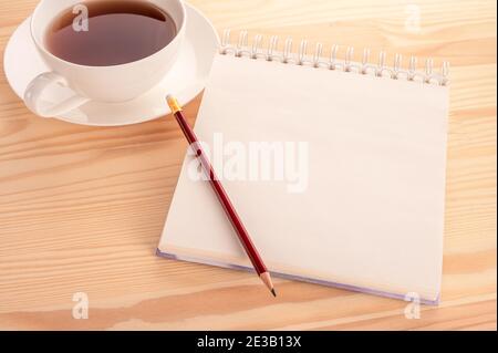 mockup notebook, pen and cup of tea on the table. Close-up. Open blank page notebook with a copy space and cup of tea on a white wooden table backgrou Stock Photo