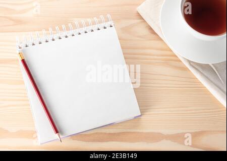 Mockup Blank notepad with pen, notebook and tea cup on wooden table. Top view notebook with blank pages Cup of Tea and red pencil on Light Wooden Back Stock Photo