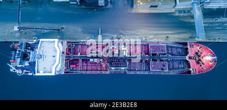 Tanker ship moored at port while unloading oil. Top down view. Stock Photo