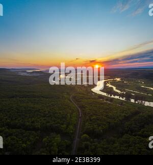 Train is running on the railroad over mountain forest in country side at summer sunset aerial view Stock Photo