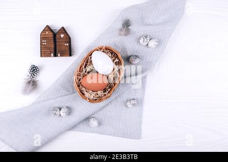 Easter eggs in the nest on textile napkin on white wooden background. Stock Photo