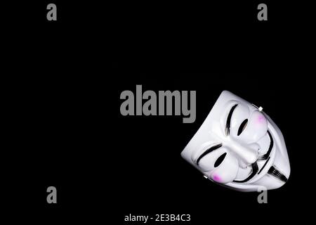Anonymous mask on black. A famous face mask of hackers, scammers and thieves Stock Photo