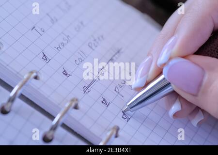 Woman putting mark on check boxes of to do list in notebook - close up Stock Photo