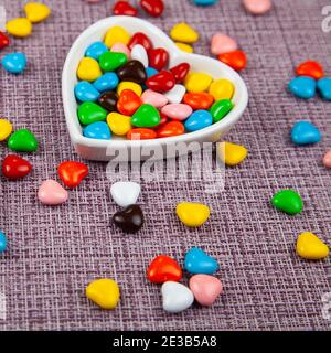 Multicolored candies in a heart-shaped plate on a  pink background. Valentine's Day. Stock Photo