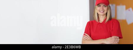 Portrait of smiling courier woman in red uniform Stock Photo