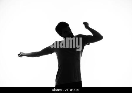 black silhouette of a man who gestures with his hands on a light ...