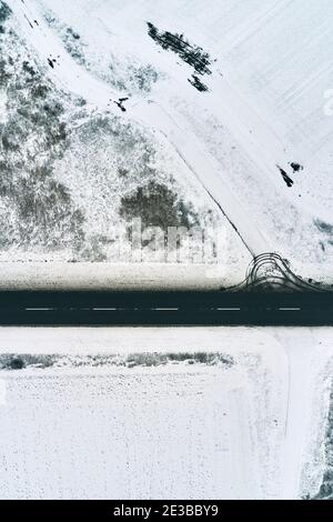 Two lane asphalt road in snowy winter morning from drone pov, aerial photography Stock Photo