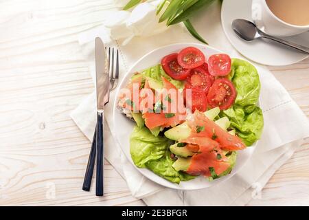 Healthy breakfast with sandwich from wholegrain bread, avocado slices and smoked on tomato and lettuce salad, white painted wooden table, copy space, Stock Photo