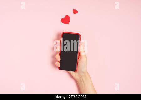 Woman's hands holding mobile phone with blank screen with heart shape Stock Photo
