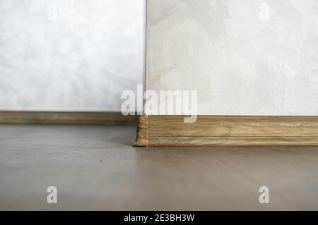 Laminate with plastic baseboard with a wooden texture. Newly installed wooden laminate flooring and baseboards in home. Modern design. Close up of Stock Photo