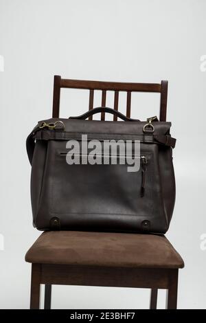 Brown men's shoulder leather bag for a documents and laptop on a brown chair with a white background. Mens leather brief case, messenger bags, leather Stock Photo