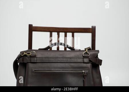 Brown men's shoulder leather bag for a documents and laptop on a brown chair with a white background. Mens leather brief case, messenger bags, leather Stock Photo