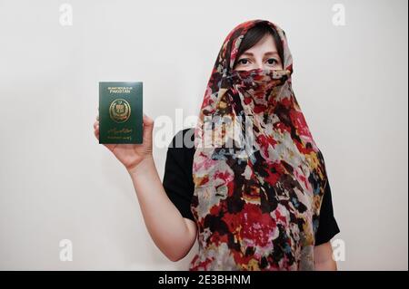 Young arabian muslim woman in hijab clothes hold Islamic Republic of Pakistan passport on white wall background, studio portrait. Stock Photo