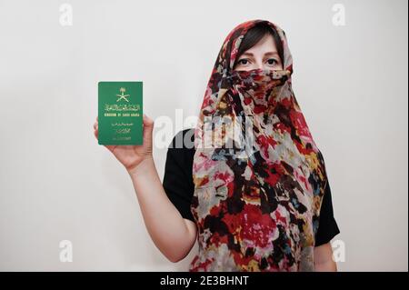 Young arabian muslim woman in hijab clothes hold Kingdom of Saudi Arabia passport on white wall background, studio portrait. Stock Photo