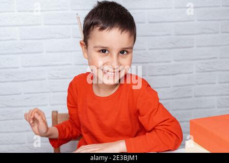 Happy schoolboy doing homework. Education, school, learning difficulties concept. Child tired of doing homework studying with pen on open books. overl Stock Photo