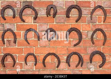 Horseshoes hanging on a brick wall, horse shoe background, UK Stock Photo