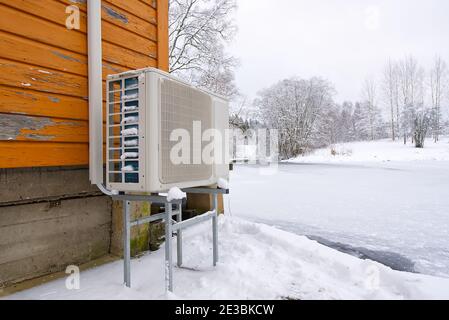 Air to water heat pump near an old wooden house in winter. air water heatpump close up Stock Photo