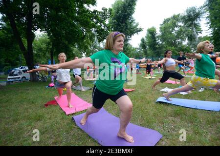 Group of middle-aged women doing morning stretching exercises at the city park. July 5, 2020. Kyiv, Ukraine Stock Photo