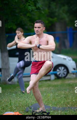Young man doing morning stretching exercises at the city park. July 5, 2020. Kyiv, Ukraine Stock Photo