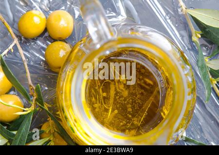 Extra virgin olive oil. Interior of a jar with olive oil seen from above twigs and bottom of the olive tree Stock Photo