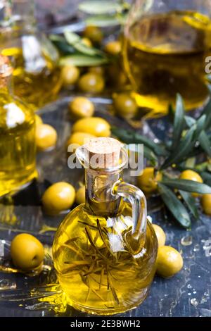 Extra virgin olive oils. Olive oil flavored with rosemary in a vintage pitcher with olives and branches.Vertical image. Stock Photo