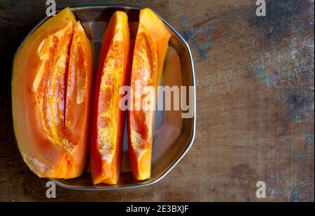 Fresh Papaya cut pieces in a plate on a wooden table Stock Photo