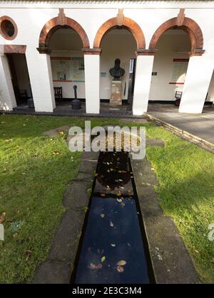 Portico and cast of a bust of Charles Darwin in an small shrine type arcade in Christs college grounds Cambridge. Stock Photo