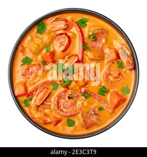 Moqueca with Fish and Shrimps in black bowl isolated on white. Brazilian sea food curry dish with coconut milk and vegetables. Stock Photo