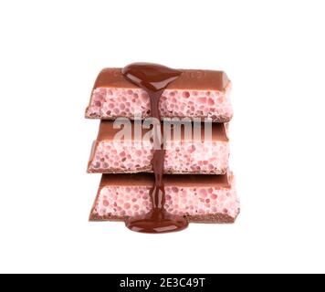 Porous chocolate pieces and chocolate syrup, isolated on white background. Pink strawberry aerated chocolate. Stock Photo