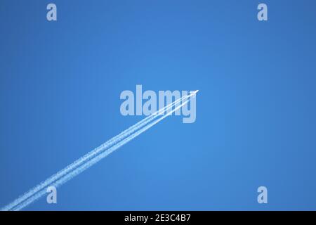 Jet airplane with white contrail. Trace of the high flying plane on the blue sky Stock Photo