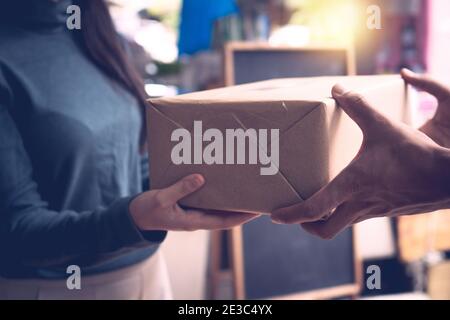 close up hand of customer woman get box parcel from delivery man Stock Photo