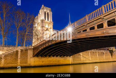 Evening view of the Notre Dame Cathedral and Pont Au Double, Paris France, during the winter from the embankment of the Seine River.