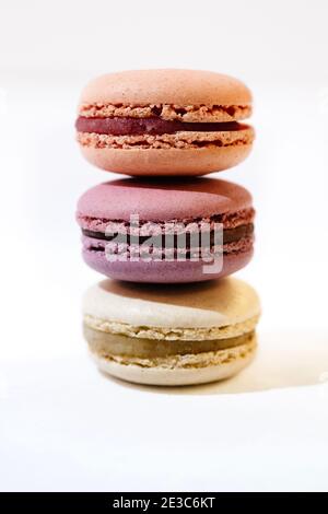 Apricot, fig and vanilla macarons stacked at a white table Stock Photo
