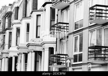 UK, West London, Notting Hill, 1973. Rundown & dilapidated large four-story houses are starting to be restored and redecorated. Near No:2 Powis Gardens. To the right are the garages of Powis Court, below the balconies, entrance in Powis Square. Stock Photo