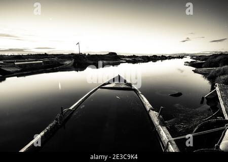 Grayscale shot of an old boat abandoned on the river Stock Photo