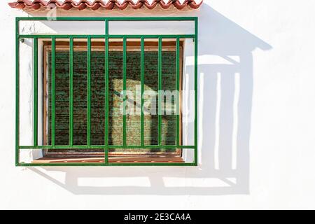 Traditional Spanish villa window with green blinds and grill in the coastal town of Oliva in the Valencian region of Spain Stock Photo