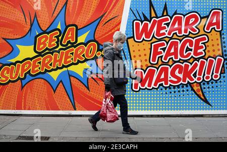 A person walks past a sign telling people to wear a face mask in Nottingham during England's third national lockdown to curb the spread of coronavirus. Picture date: Monday January 18, 2021. Stock Photo