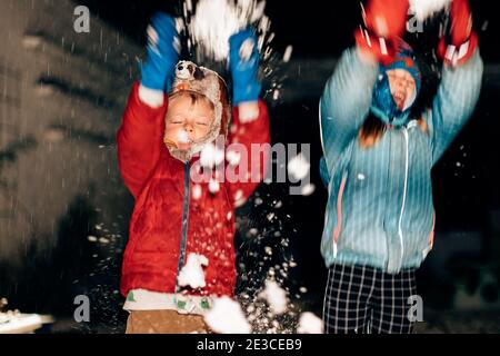 kids playing with the snow outdoor in the backyard on a cold night Stock Photo