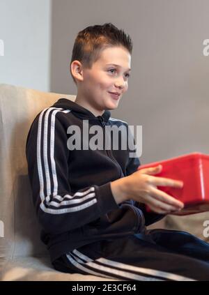Handsome happy smiling 13 year old teenage boy receiving a wrapped present Stock Photo