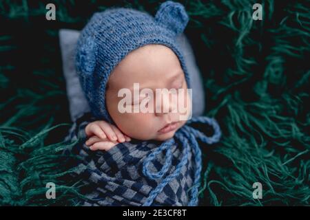 Cute sleeping newborn wearing blue knitted hat Stock Photo