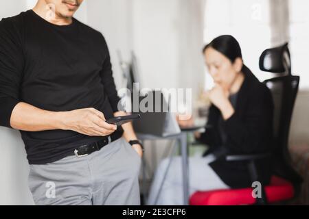 Businessman using mobile phone while woman working in background. Stock Photo