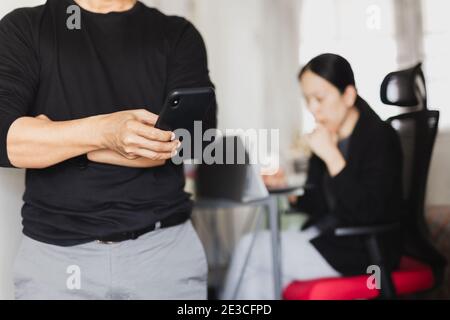 Businessman using mobile phone while woman working in background. Stock Photo