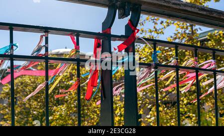 Coloured ribbons knotted to the river bridge, symbolising friendship and love written with messages en Portugal Stock Photo