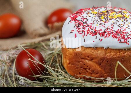 Festive Easter cake on a light background, decorated with multi-colored dragees. Painted Easter eggs as an attribute of Easter. Close-up. Studio light Stock Photo