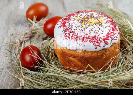 Festive Easter cake on a light background, decorated with multi-colored dragees. Painted Easter eggs as an attribute of Easter. Close-up. Studio light Stock Photo