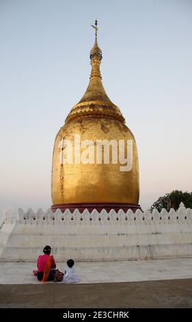 Mother and child praying at the golden dome of the Bupaya Pagoda Bagan Pagan Myanmar Burma Stock Photo