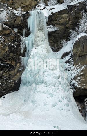A photograph of a frozen waterfall in Saas-Balen in winter. Saas-Balen is a municipality in the district of Visp in the canton of Valais, Switzerland. Stock Photo