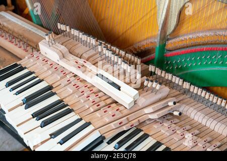 Setting up an old piano. The master repairs an old piano. Deep cleaning the piano. Hands of professional worker repairing and tuning an old piano Stock Photo