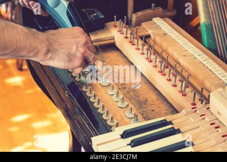 Setting up an old piano. The master repairs an old piano. Deep cleaning the piano. Hands of professional worker repairing and tuning an old piano Stock Photo